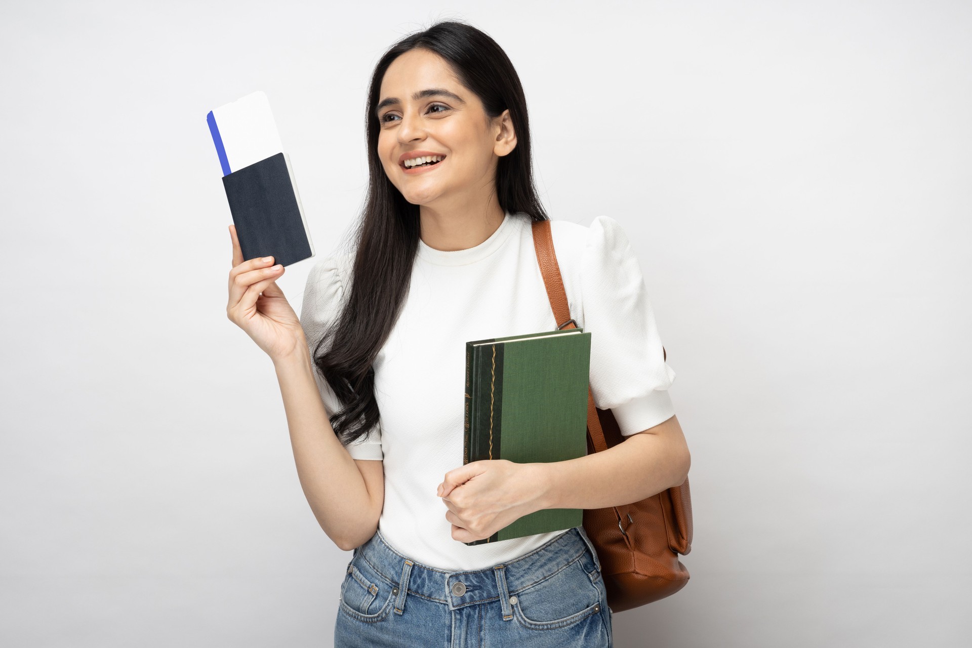 Portrait of young women student showing plane ticket and passport standing isolated over white background:- stock photo