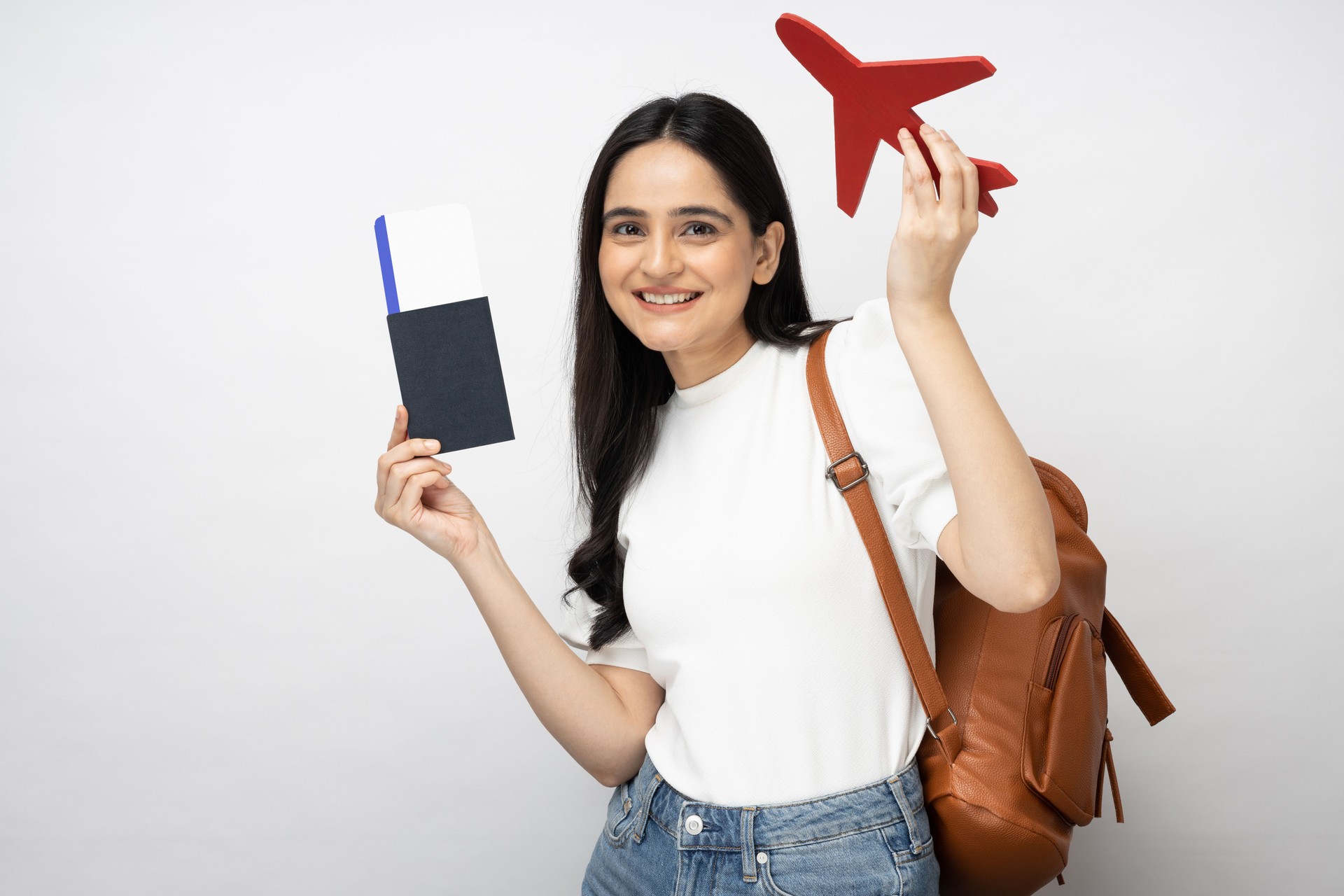 Portrait of young women student showing plane ticket and passport standing isolated over white background:- stock photo